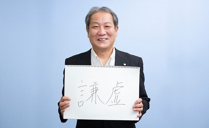 「謙虚」の文字を掲げる青山